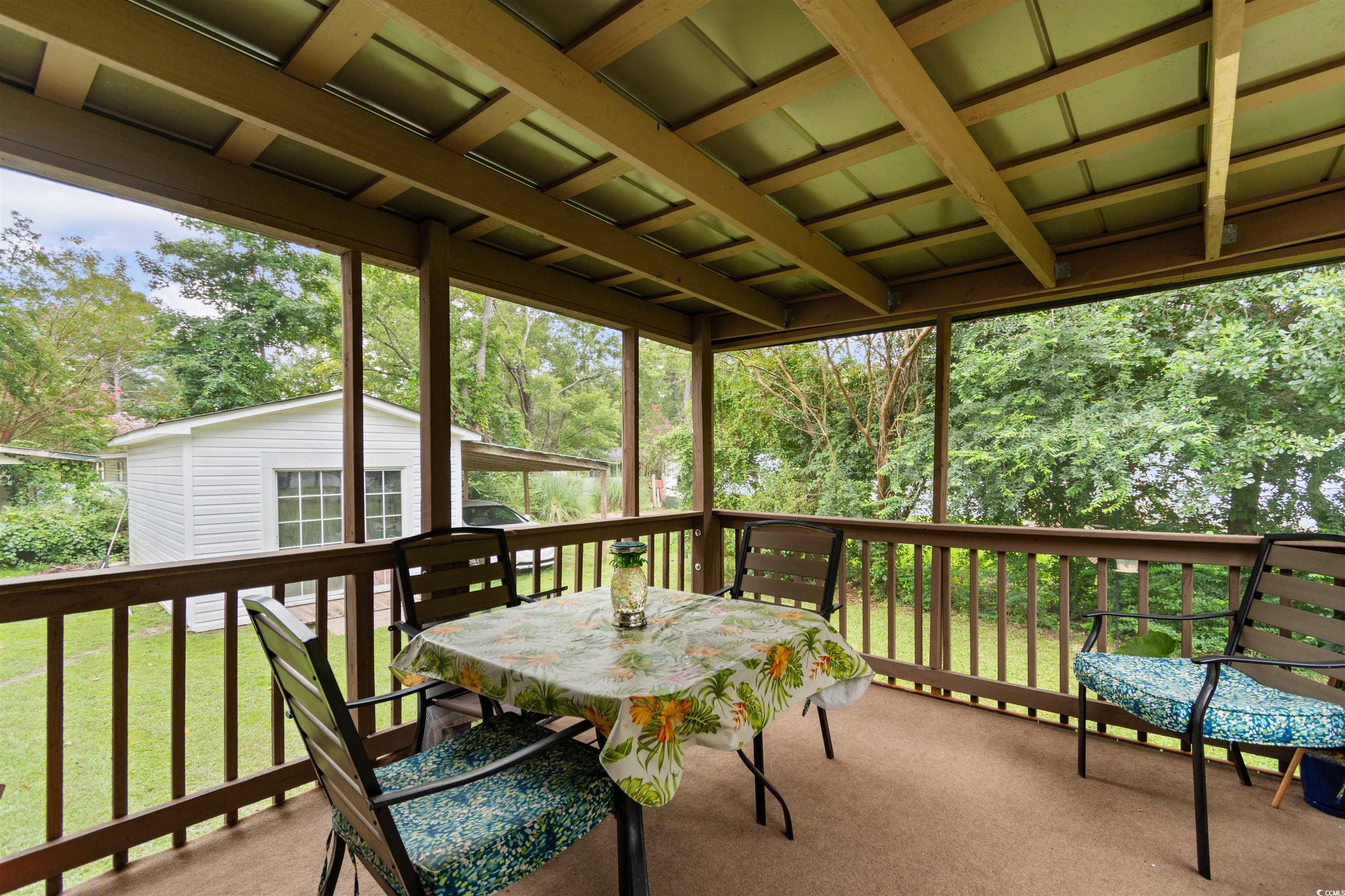 11140 Mcdowell Shortcut Road Murrells Inlet, SC 29576 - Photo 26 of 33 Wooden deck with outdoor dining area, an outdoor structure, a yard, and view of scattered trees