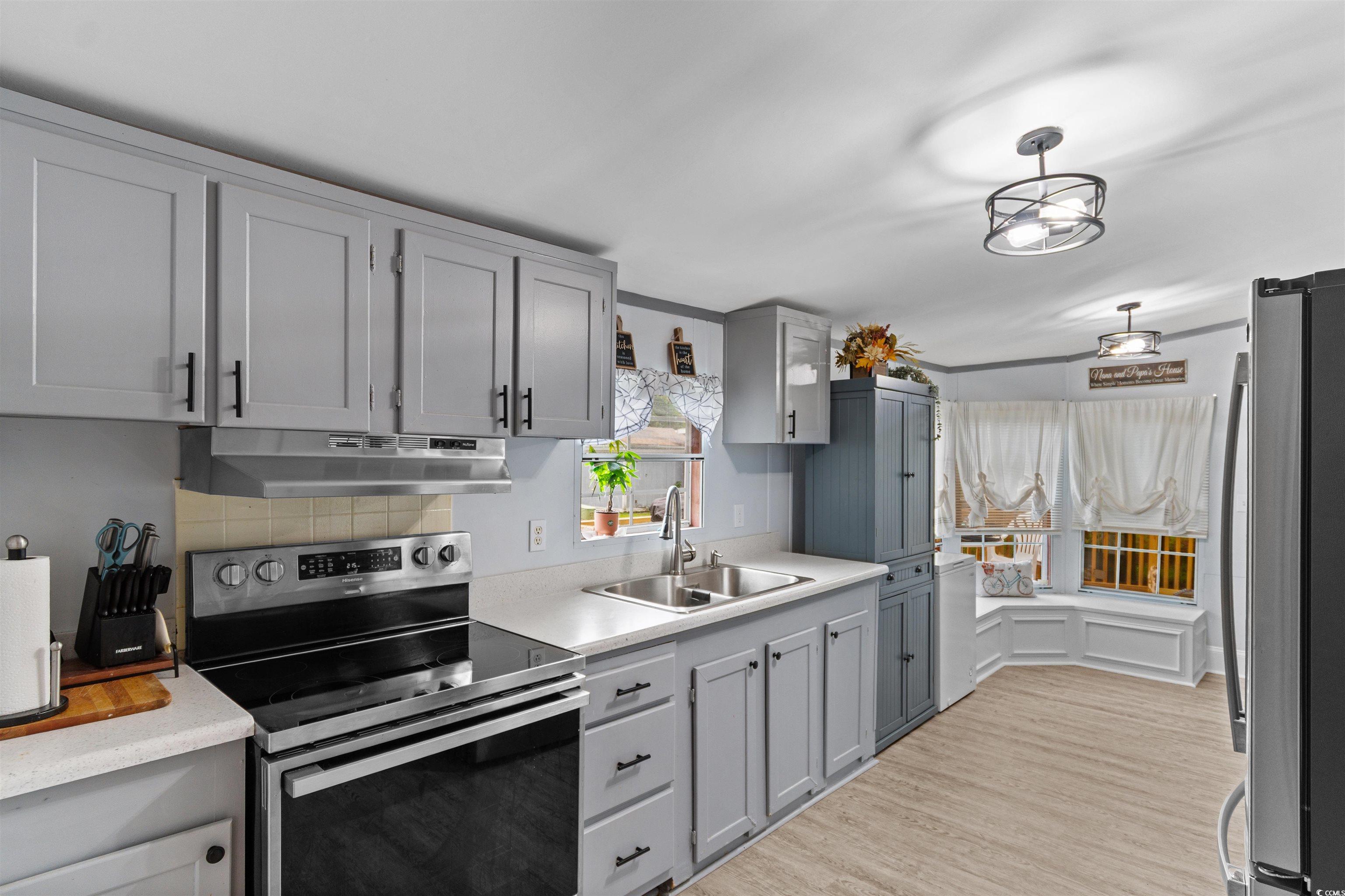 11140 Mcdowell Shortcut Road Murrells Inlet, SC 29576 - Photo 4 of 33 Kitchen with stainless steel appliances, light countertops, light wood-style floors, under cabinet range hood, and gray cabinets