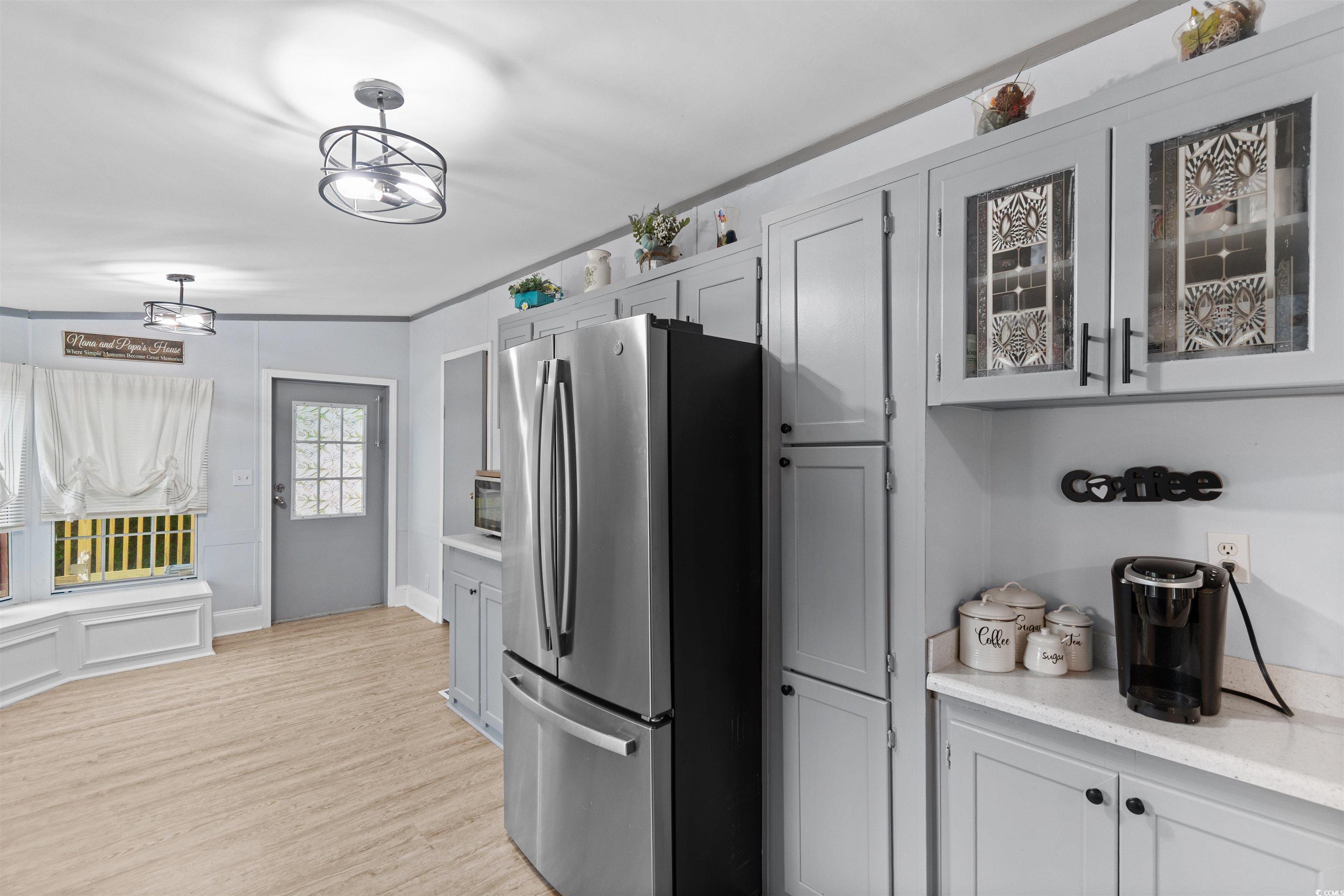 11140 Mcdowell Shortcut Road Murrells Inlet, SC 29576 - Photo 5 of 33 Kitchen with freestanding refrigerator, light wood finished floors, light countertops, glass insert cabinets, and ornamental molding