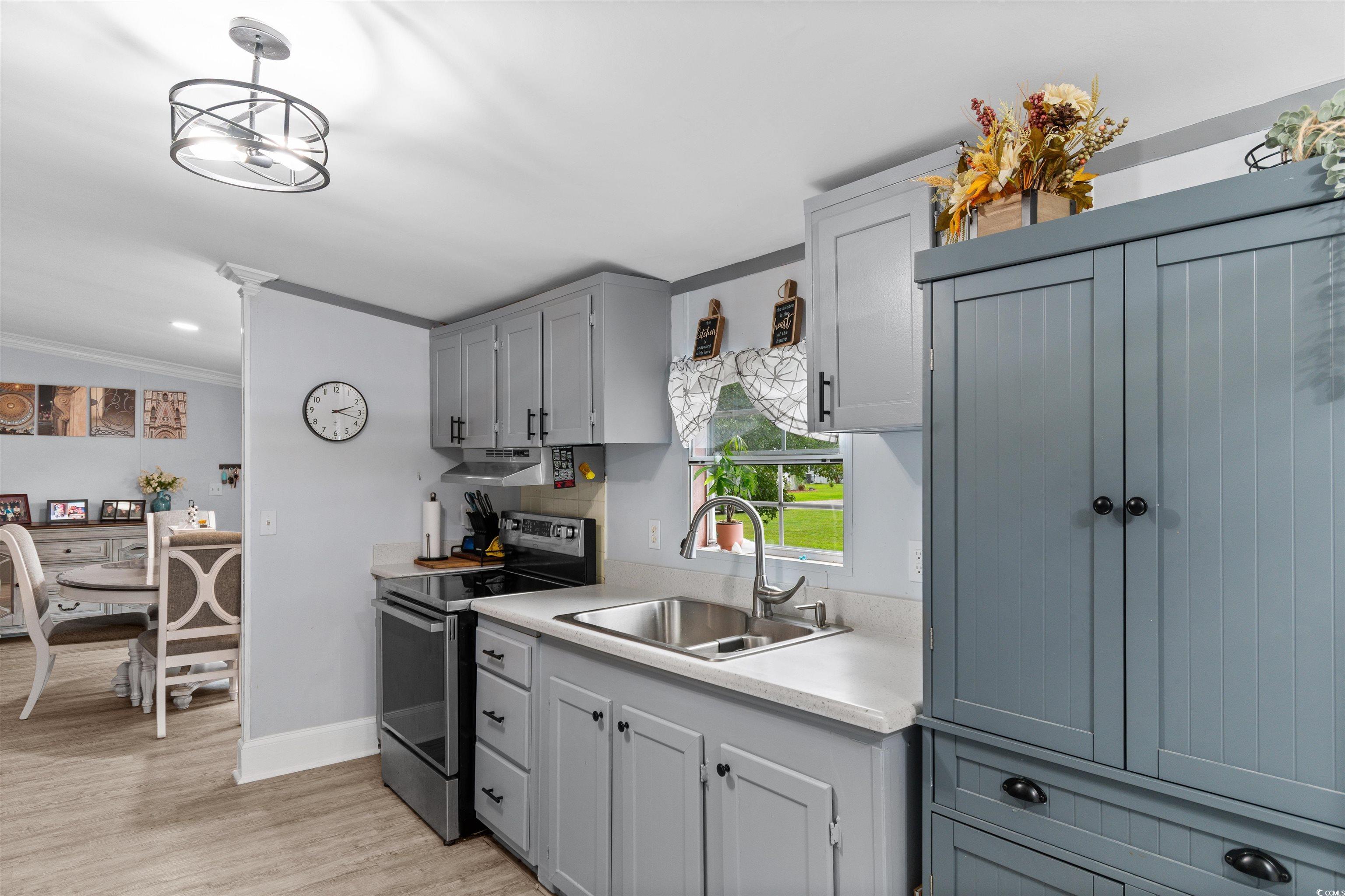 11140 Mcdowell Shortcut Road Murrells Inlet, SC 29576 - Photo 6 of 33 Kitchen featuring stainless steel electric stove, light wood-style flooring, light countertops, and ornamental molding