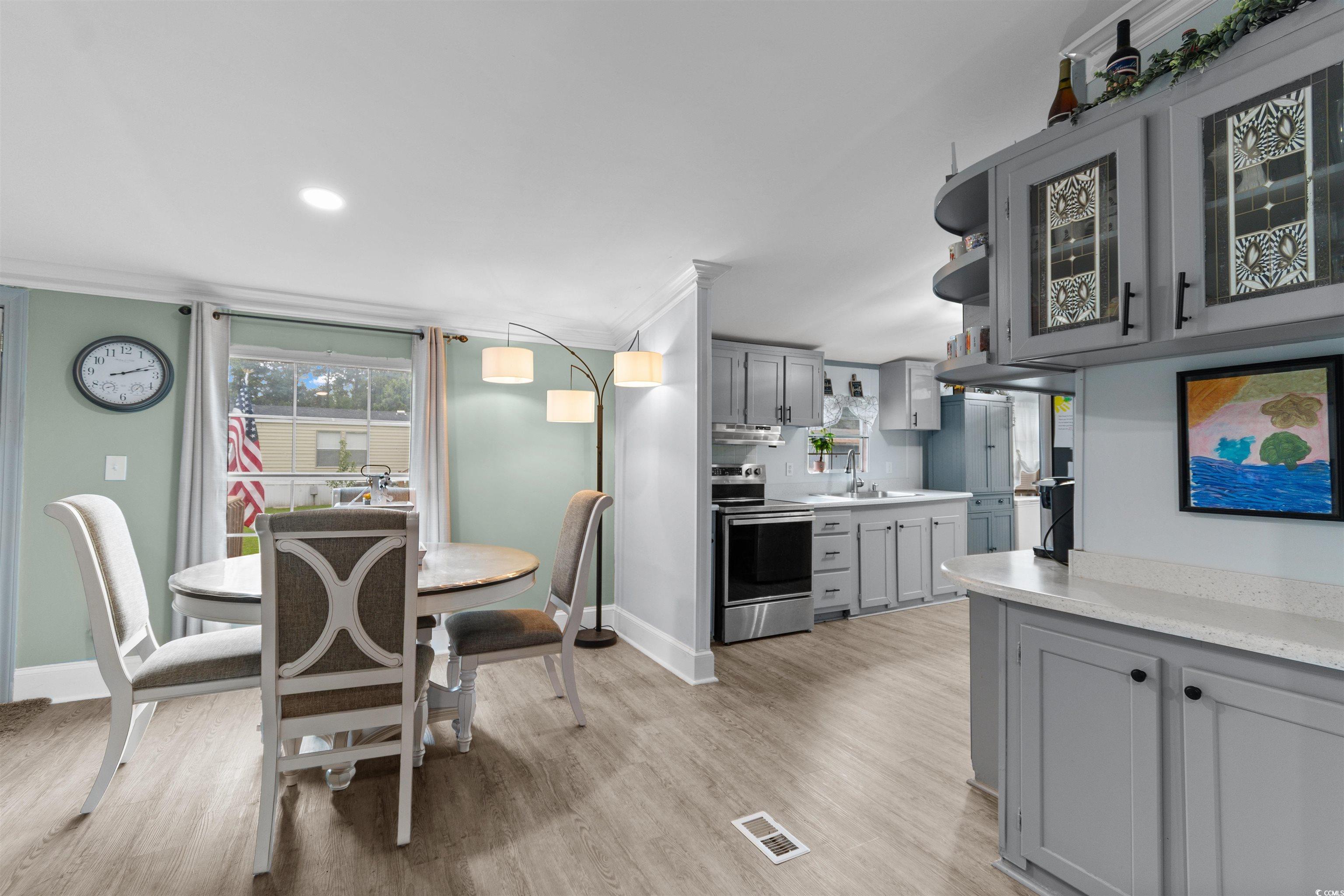 11140 Mcdowell Shortcut Road Murrells Inlet, SC 29576 - Photo 7 of 33 Kitchen with gray cabinetry, light countertops, crown molding, light wood finished floors, and stainless steel range with electric stovetop