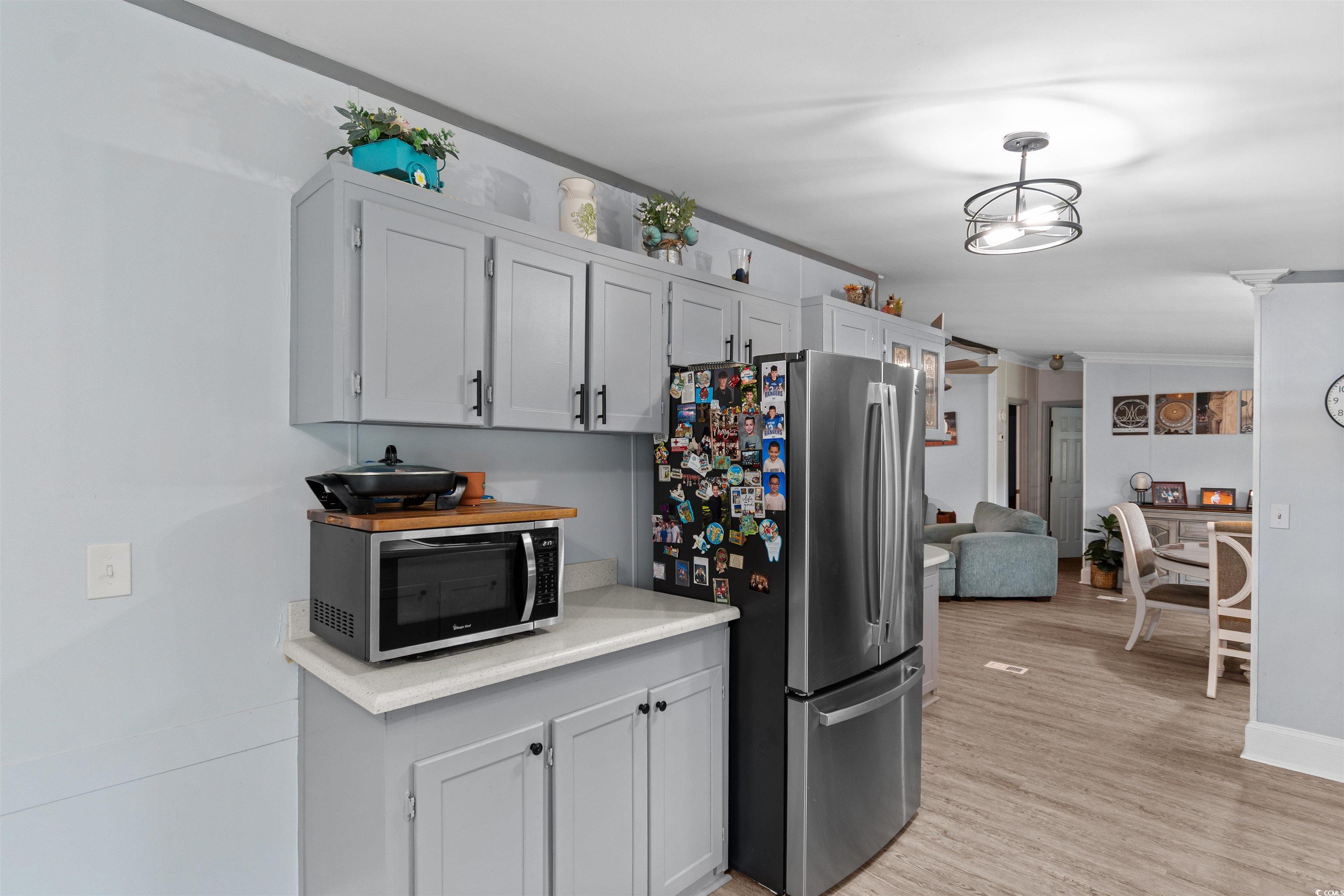 11140 Mcdowell Shortcut Road Murrells Inlet, SC 29576 - Photo 8 of 33 Kitchen with appliances with stainless steel finishes, light countertops, light wood-type flooring, and ornamental molding