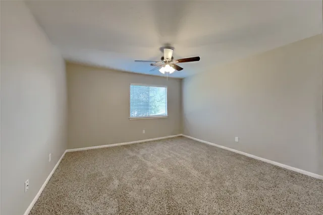 an empty room with a chandelier fan and windows
