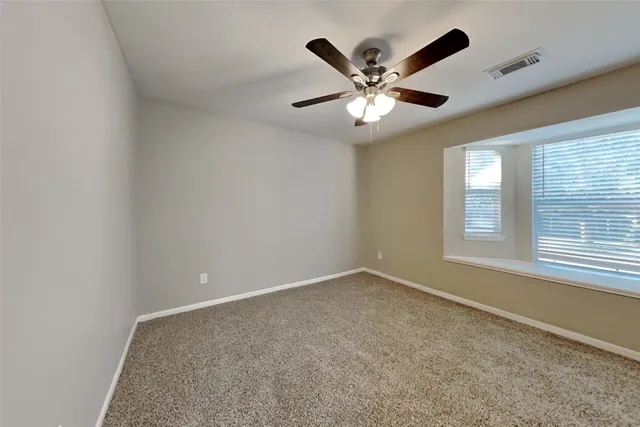 an empty room with windows and fan