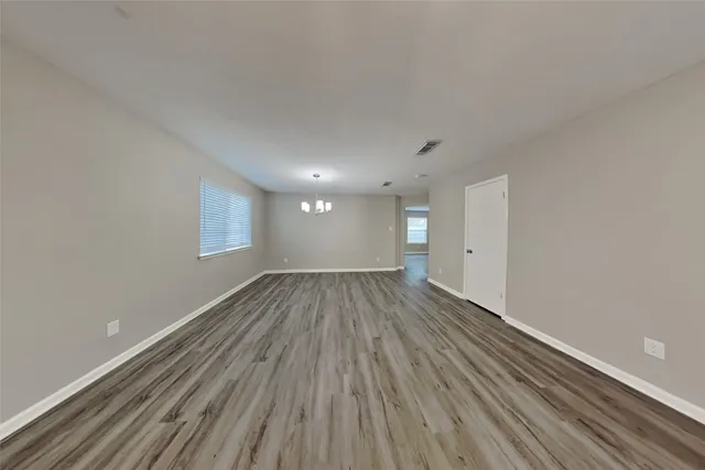 a view of an empty room with wooden floor and window