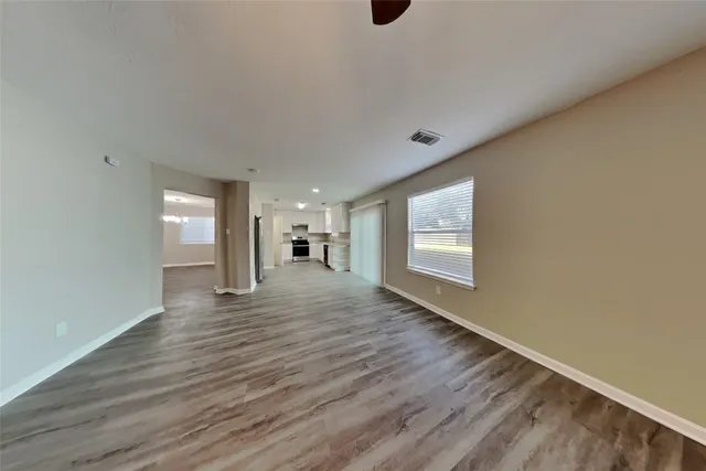 a view of an empty room with wooden floor and a window