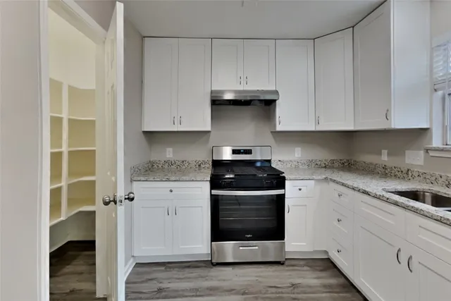 a kitchen with granite countertop white cabinets and stainless steel appliances