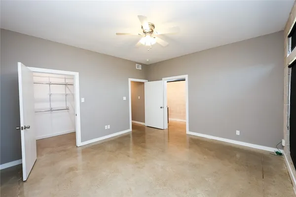 an empty room with closet and a ceiling fan