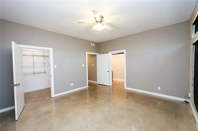 an empty room with closet and a ceiling fan