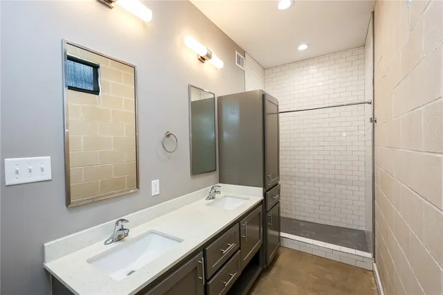 a bathroom with a double vanity sink a large mirror and shower