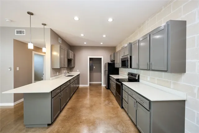 a large kitchen with stainless steel appliances lots of counter space and wooden floor