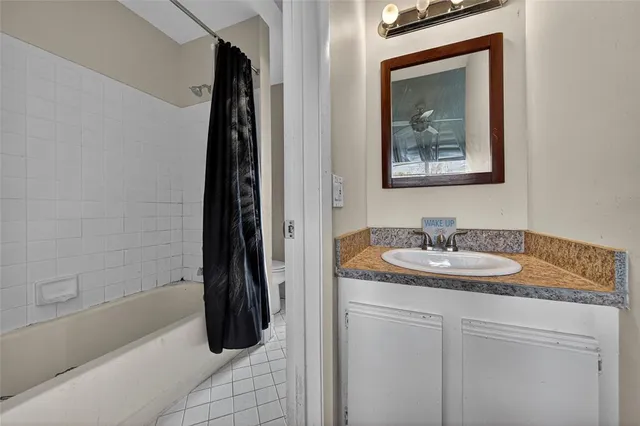 a bathroom with a granite countertop sink a mirror and shower