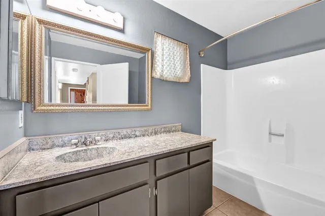 a bathroom with a granite countertop sink a mirror a vanity and bathtub
