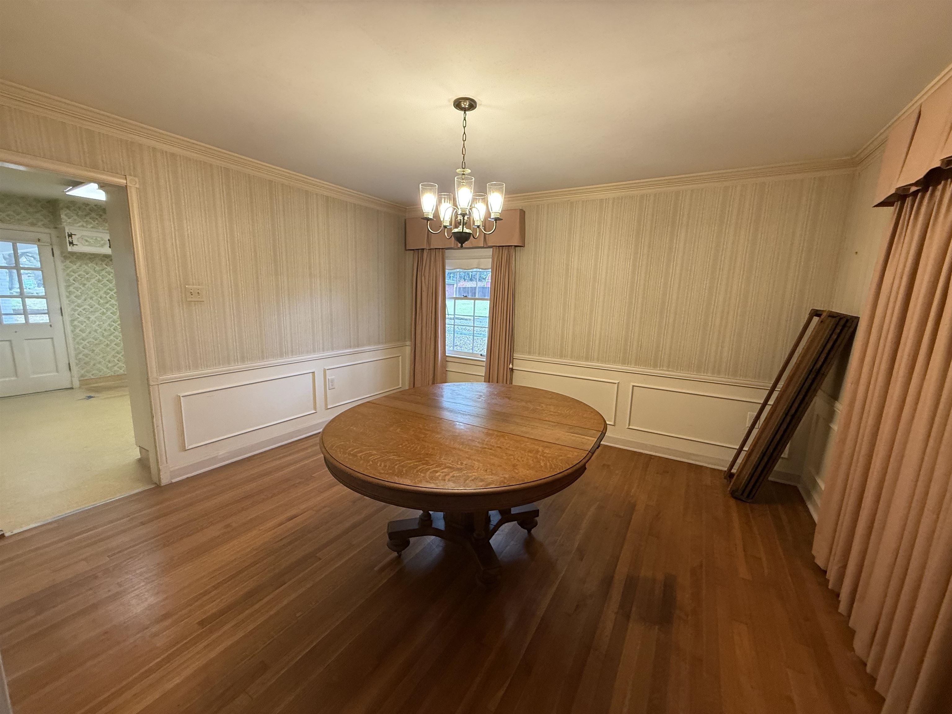 5575 Walnut Grove Road Memphis, TN 38120 - Photo 15 of 36 Dining area with hardwood / wood-style floors, a chandelier, wallpapered walls, and a wainscoted wall