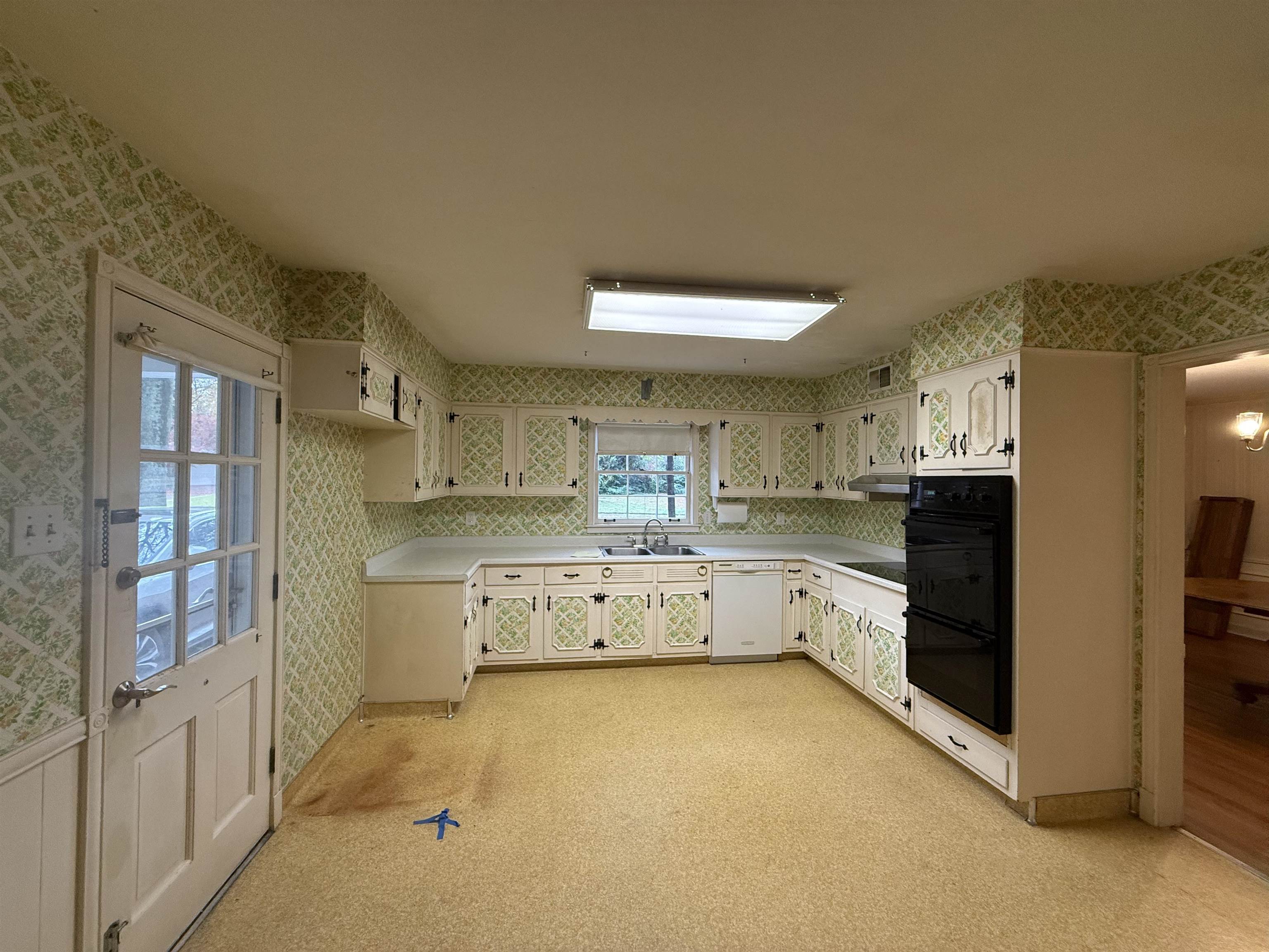 5575 Walnut Grove Road Memphis, TN 38120 - Photo 19 of 36 Kitchen with wallpapered walls, light countertops, black appliances, light colored carpet, and white cabinets