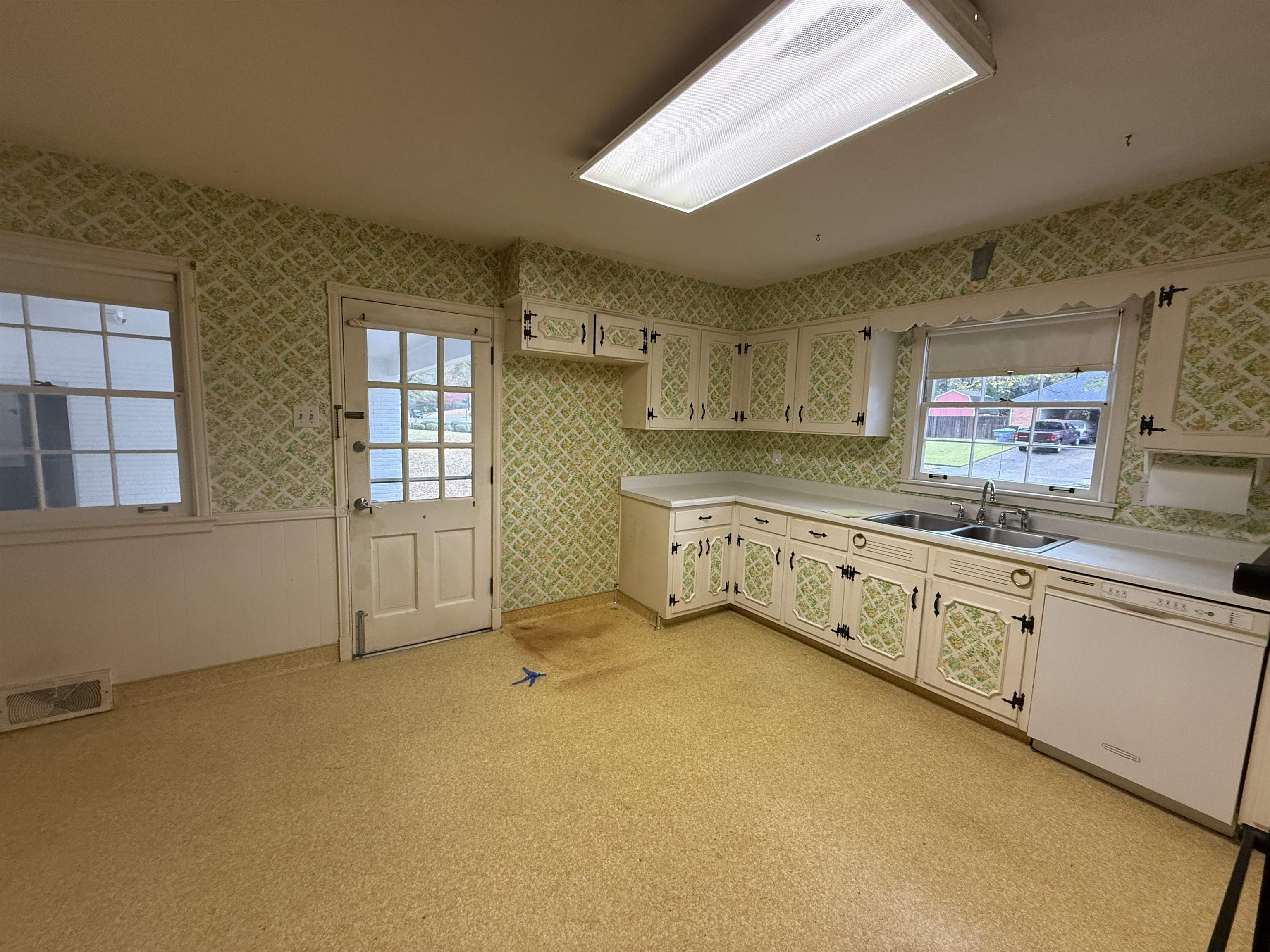 5575 Walnut Grove Road Memphis, TN 38120 - Photo 20 of 36 Kitchen featuring light countertops, white dishwasher, wallpapered walls, a wainscoted wall, and light carpet