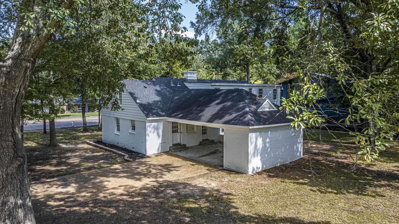 5575 Walnut Grove Road Memphis, TN 38120 - Photo 8 of 36 Back of property with a shingled roof, brick siding, a carport, view of scattered trees, and dirt driveway