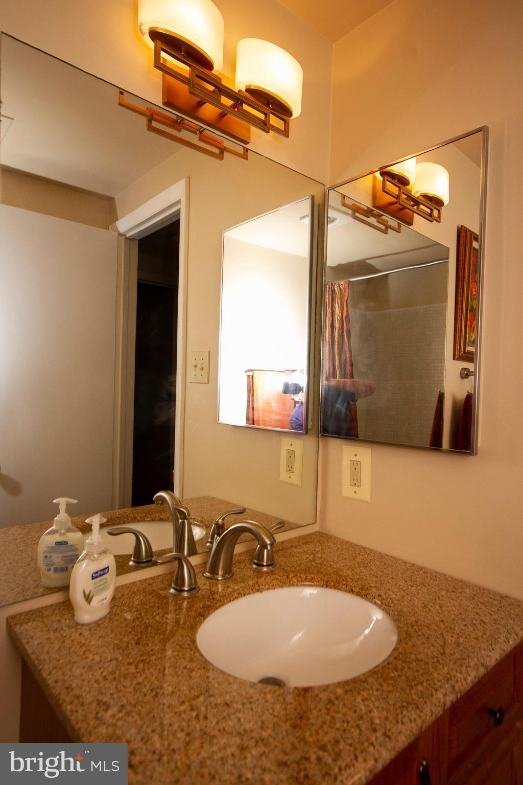 14 Cross Keys Road, Unit 14D Baltimore, MD 21210 - Photo 25 of 25 a bathroom with a granite countertop sink and a mirror