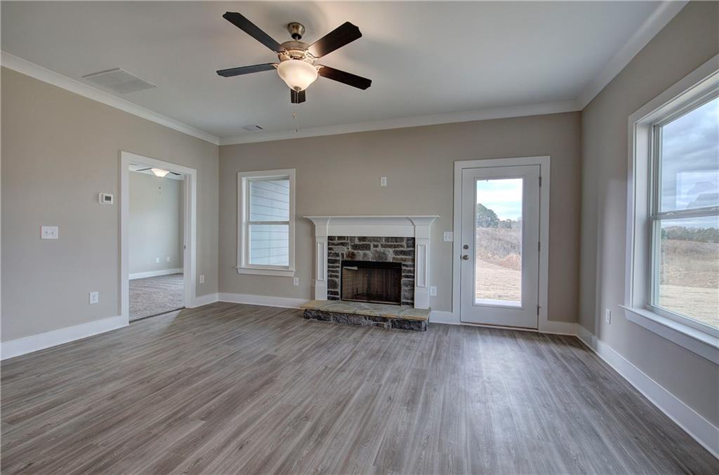 201 Daisy Court Cartersville, GA 30121 - Photo 7 of 36 an empty room with windows a fireplace a ceiling fan and wooden floor