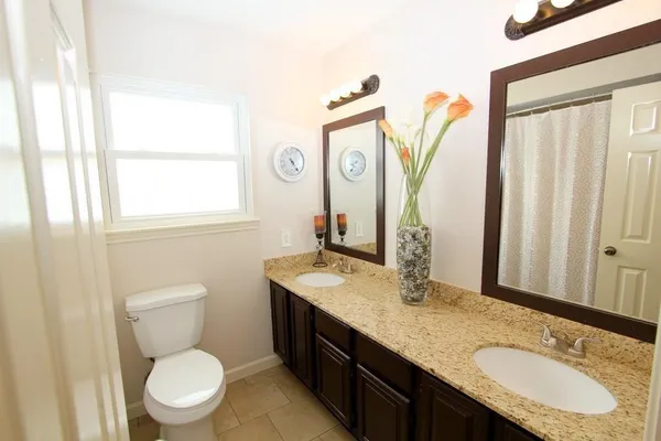 a bathroom with a granite countertop toilet sink and mirror