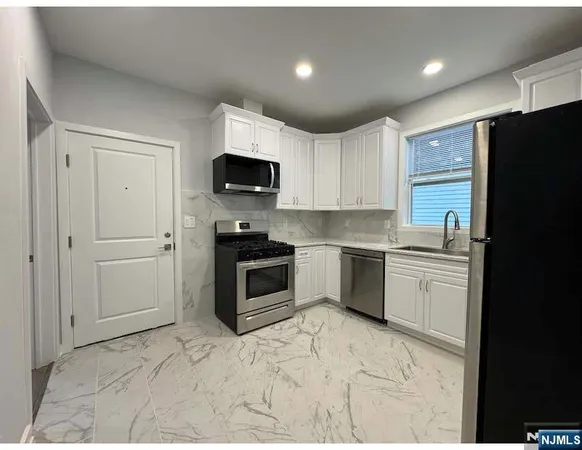 a kitchen with granite countertop a refrigerator stove and sink