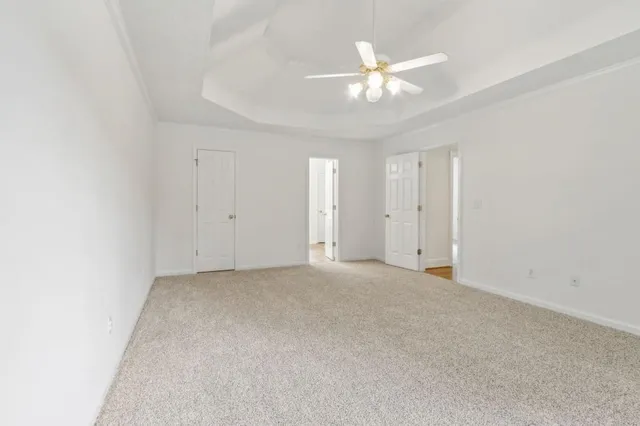 an empty room with a chandelier fan and a window