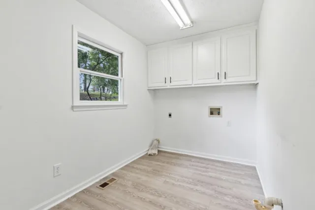 a view of a hallway with wooden floor and a bathroom