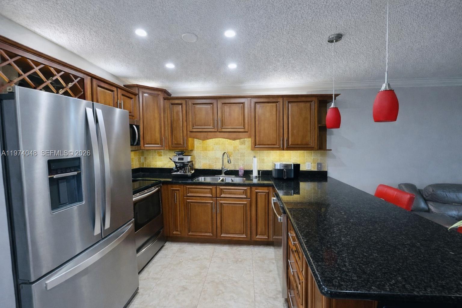 13890 Southwest 64th Street Miami, FL 33183 - Photo 10 of 23 a kitchen with granite countertop stainless steel appliances and wooden cabinets