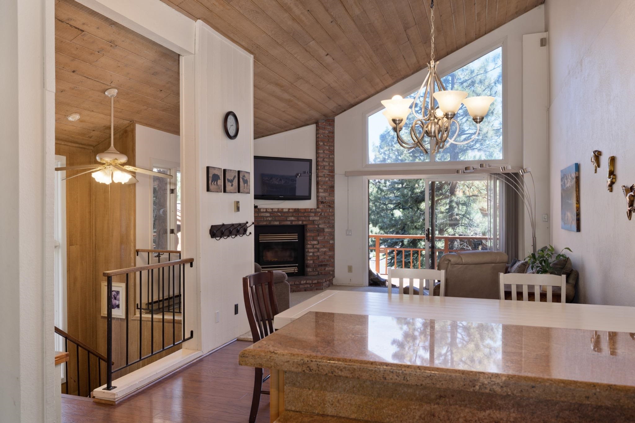3392 Chateau Road, Unit 29 Mammoth Lakes, CA 93546 - Photo 11 of 30 Open-concept living space featuring vaulted wood-finish ceilings, an exposed brick fireplace, and a