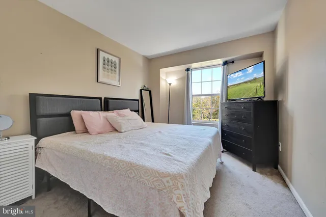 a bedroom with a bed and a flat tv screen on dresser