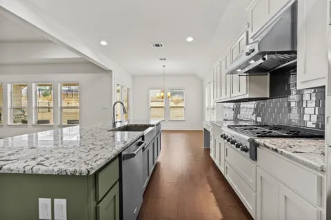 a kitchen with granite countertop sink stove and cabinets