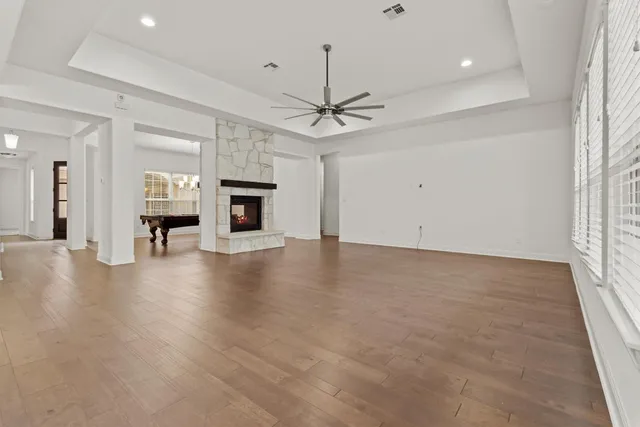 an empty room with wooden floor fireplace and a chandelier