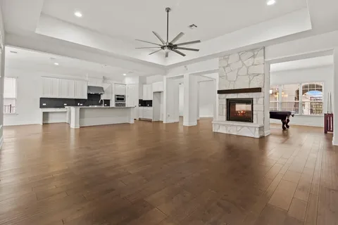 a view of a livingroom with furniture a fireplace wooden floor and a ceiling fan