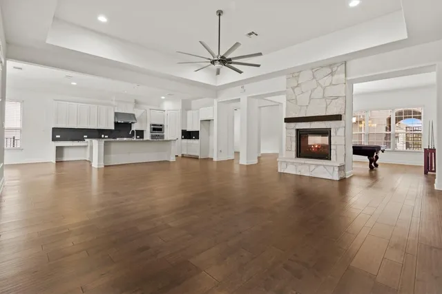 a view of a livingroom with furniture a fireplace wooden floor and a ceiling fan