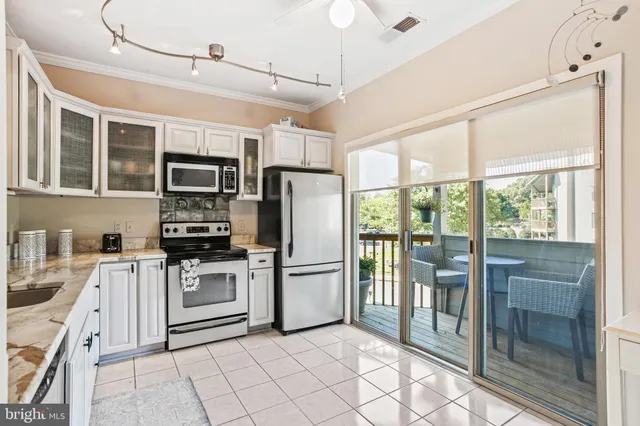 a kitchen with granite countertop a refrigerator a sink a stove top oven and cabinets