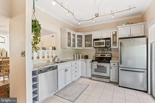 a kitchen with stainless steel appliances granite countertop a refrigerator a stove a sink and white cabinets