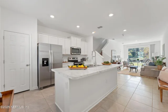 a view of kitchen with stainless steel appliances refrigerator stove dining table and chairs