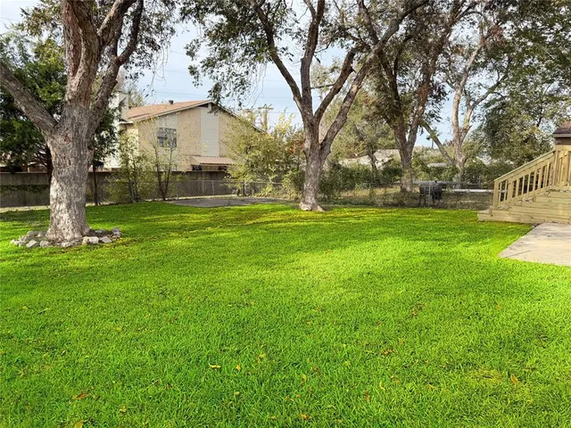 a white house with a big yard and large trees