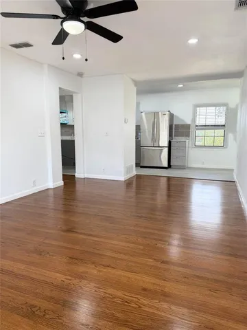 a view of an empty room with window and wooden floor