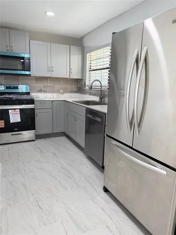a kitchen with stainless steel appliances granite countertop a refrigerator sink and microwave