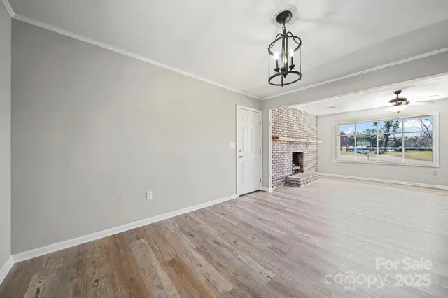 a view of a room with wooden floor ceiling fan and windows