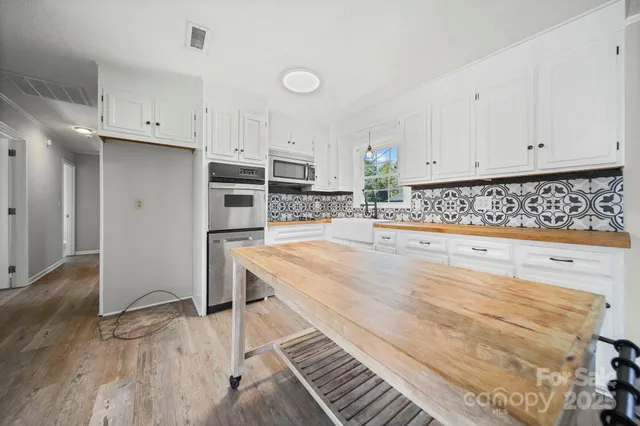a kitchen with granite countertop white cabinets and stainless steel appliances