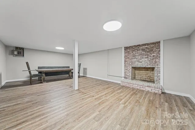 a view of an empty room with wooden floor and fireplace