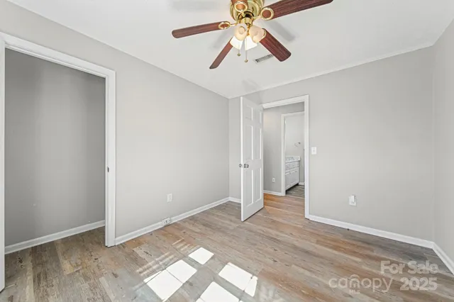 an empty room with wooden floor and ceiling fan