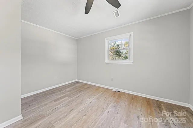 an empty room with a ceiling fan and window