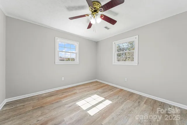 a view of an empty room with window and a chandelier fan