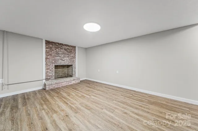 a view of empty room with wooden floor and fireplace