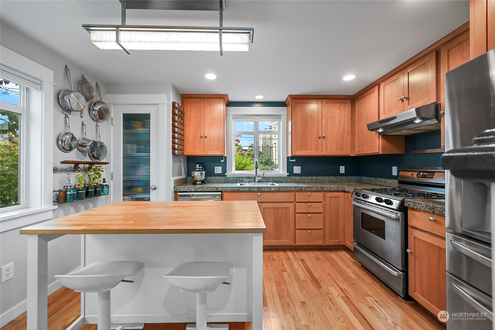4408 Meridian Avenue North, Unit A Seattle, WA 98103 - Photo 5 of 31 a kitchen with stainless steel appliances granite countertop a kitchen island hardwood floor sink stove and wooden cabinets