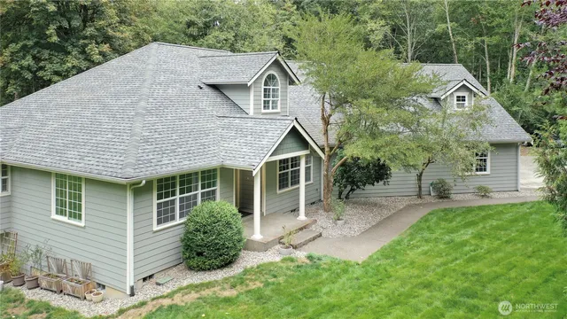 a view of a house with a yard plants and large tree