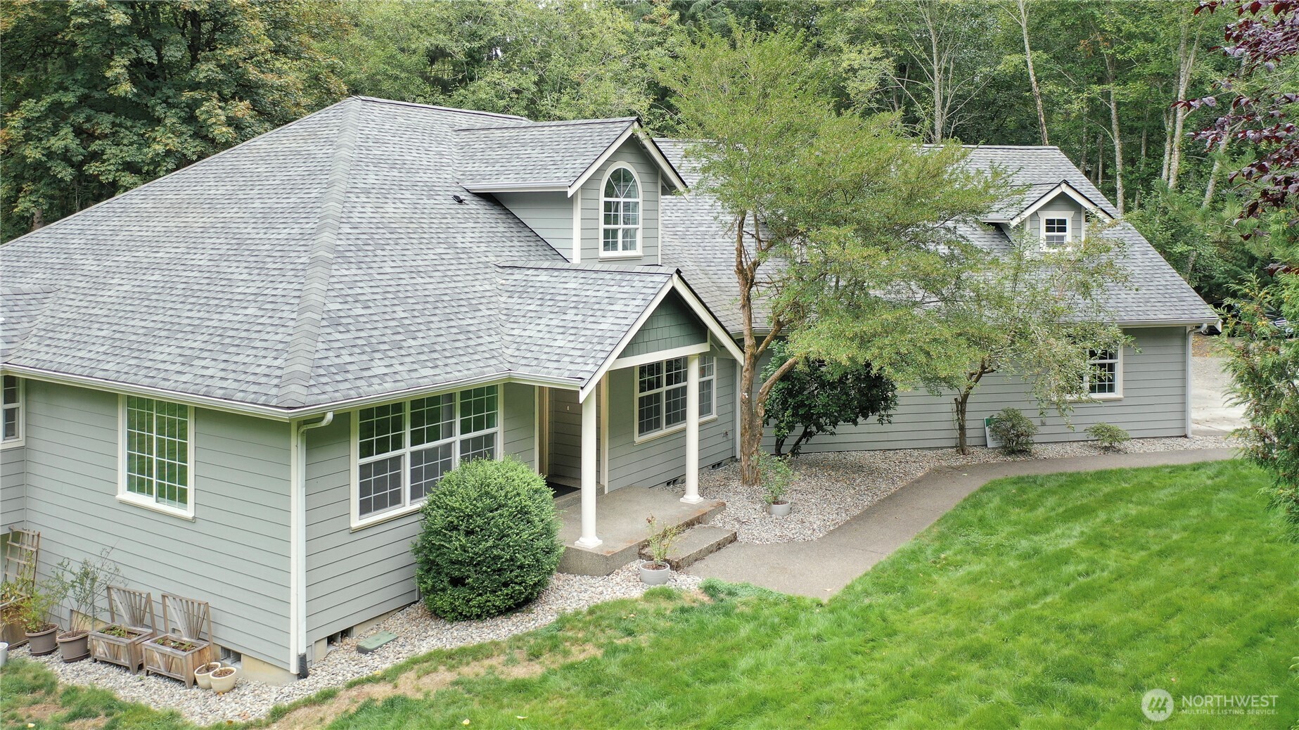 a view of a house with a yard plants and large tree